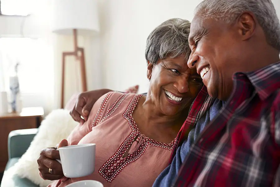 Medicare - Loving Couple Sitting on the Sofa at Home Relaxing with Coffee on the Couch